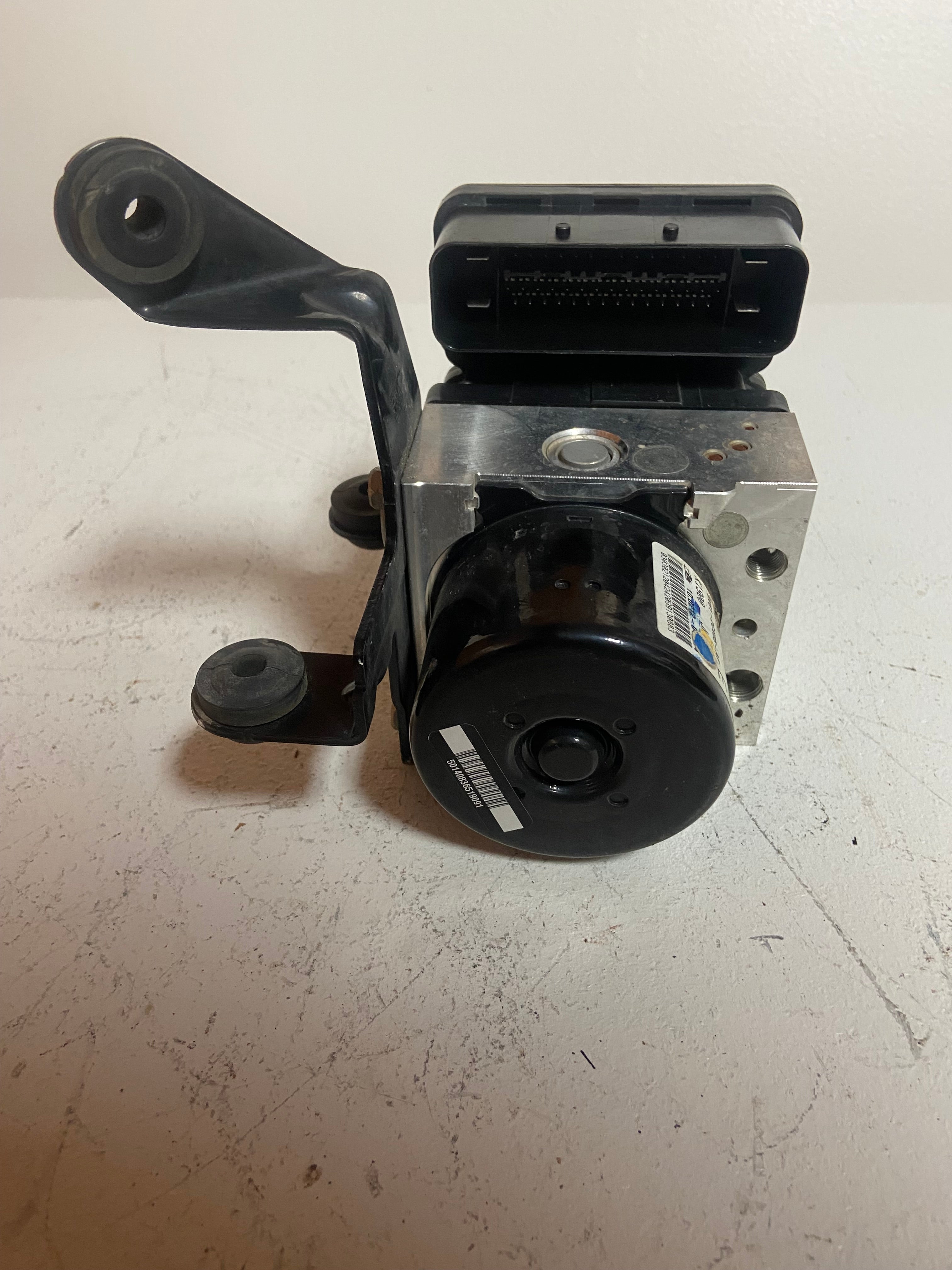 ABS pump control module with round pump cover and top wiring connector.