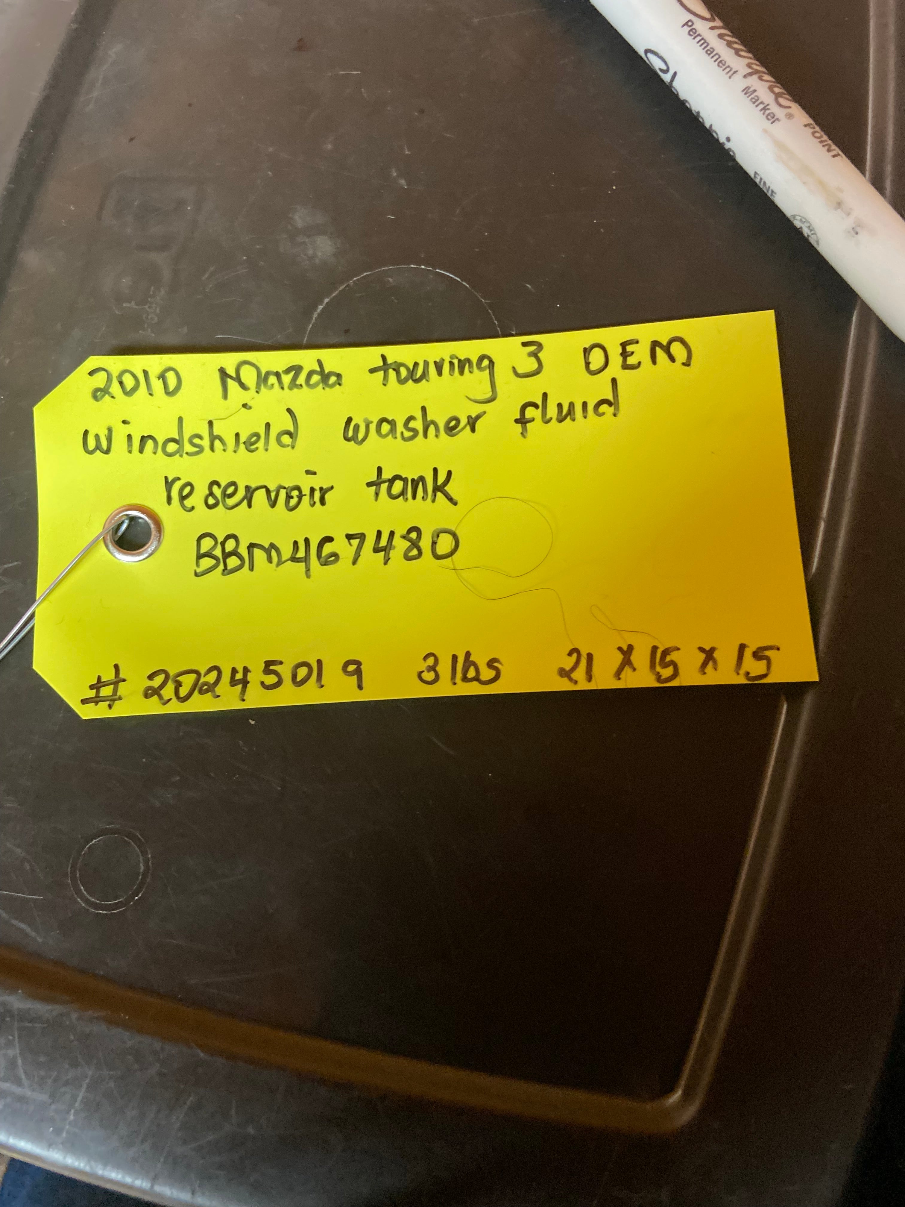 Windshield washer fluid reservoir tank with handwritten label and part number BBM467480