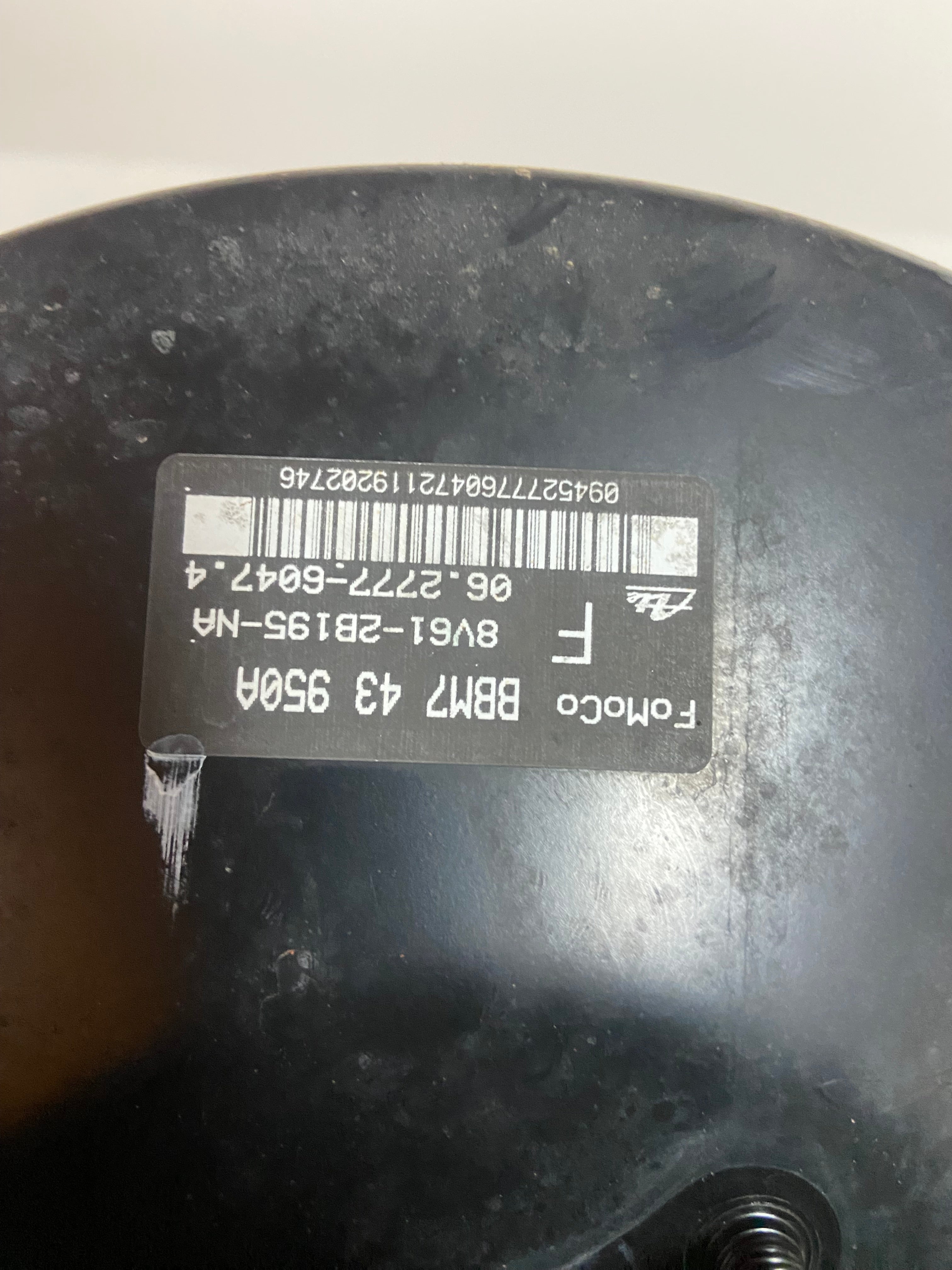 Black power brake booster side with barcode label and threaded opening