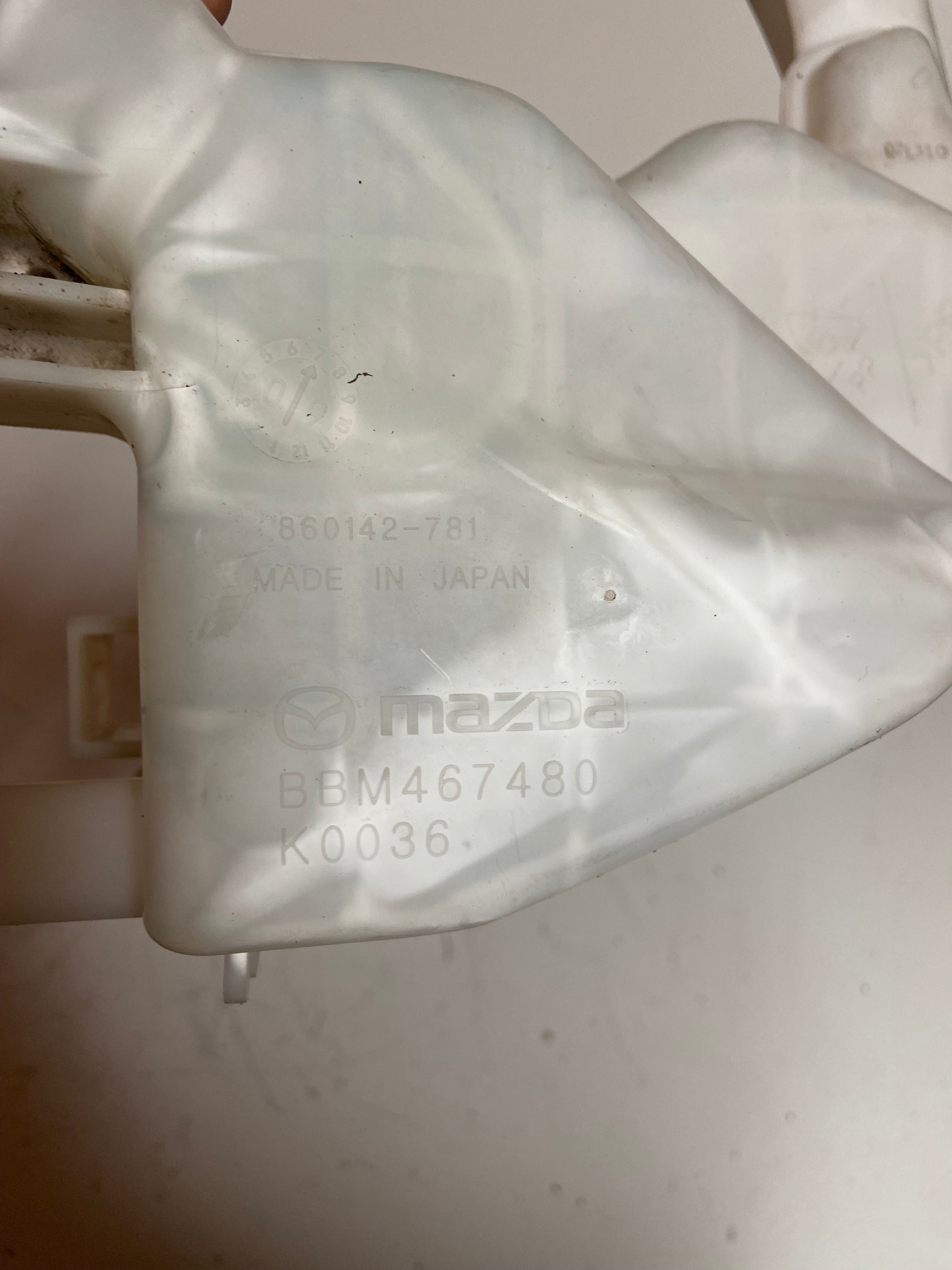 Washer fluid reservoir tank with printed Mazda markings and made-in-Japan text