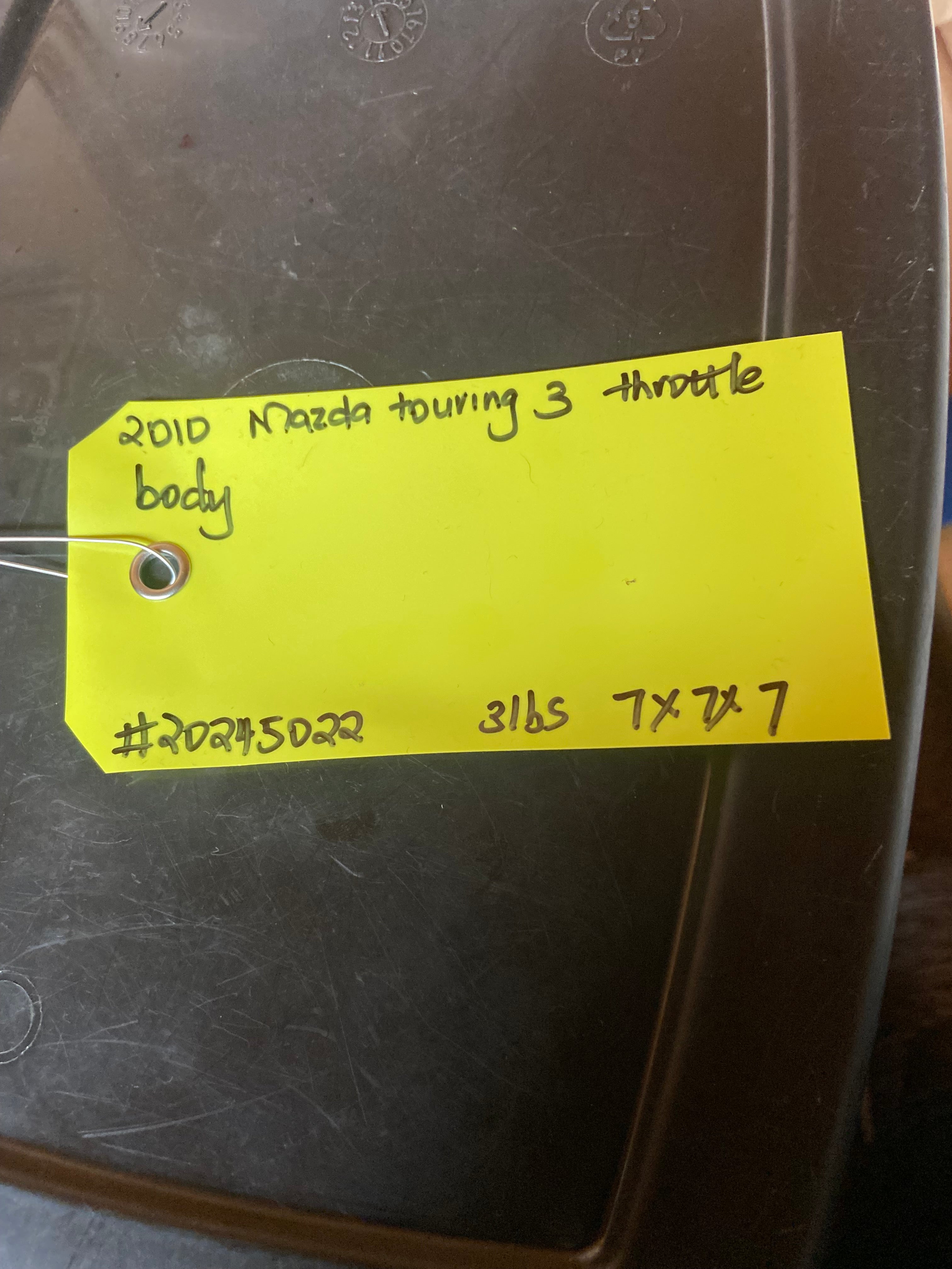 Automotive throttle body housing with handwritten inventory tag on top