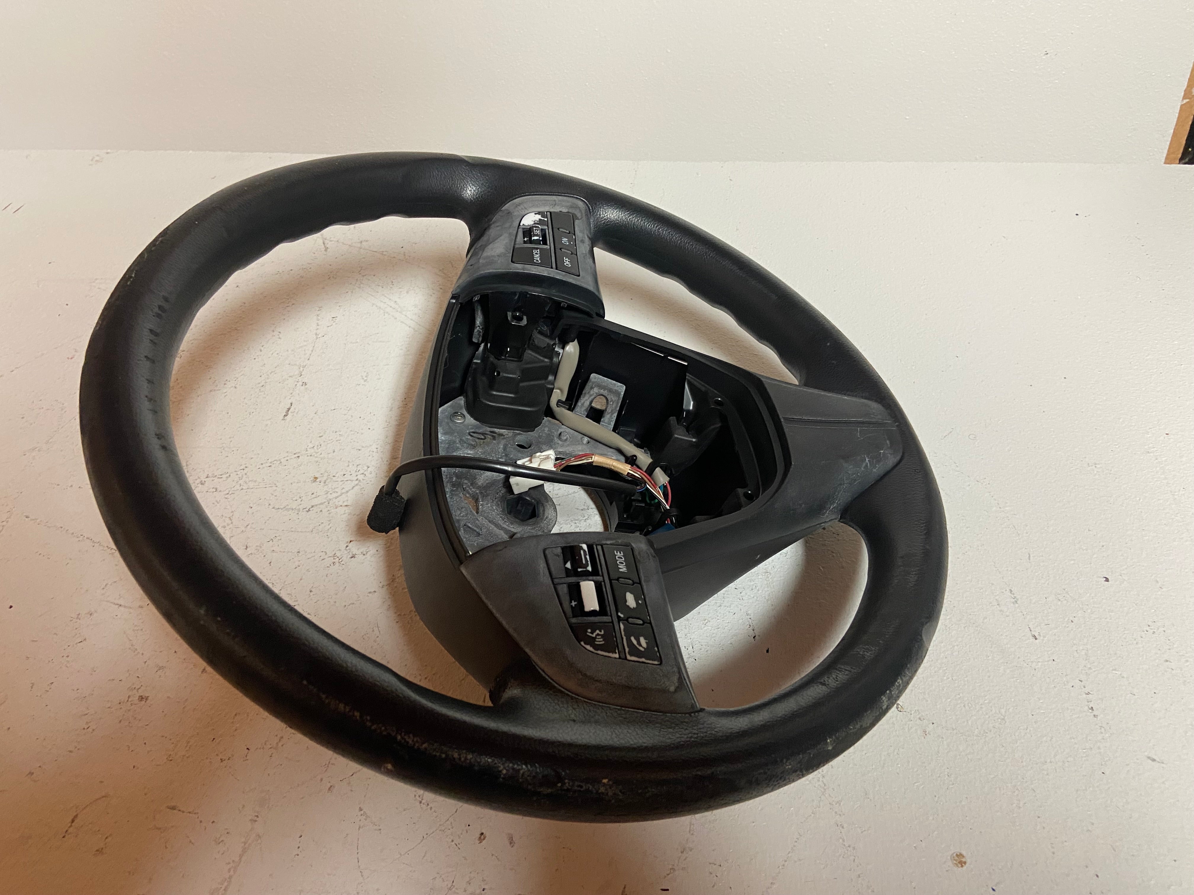 Black OEM steering wheel for 2010 Mazda 3 touring, side rear view showing control switches