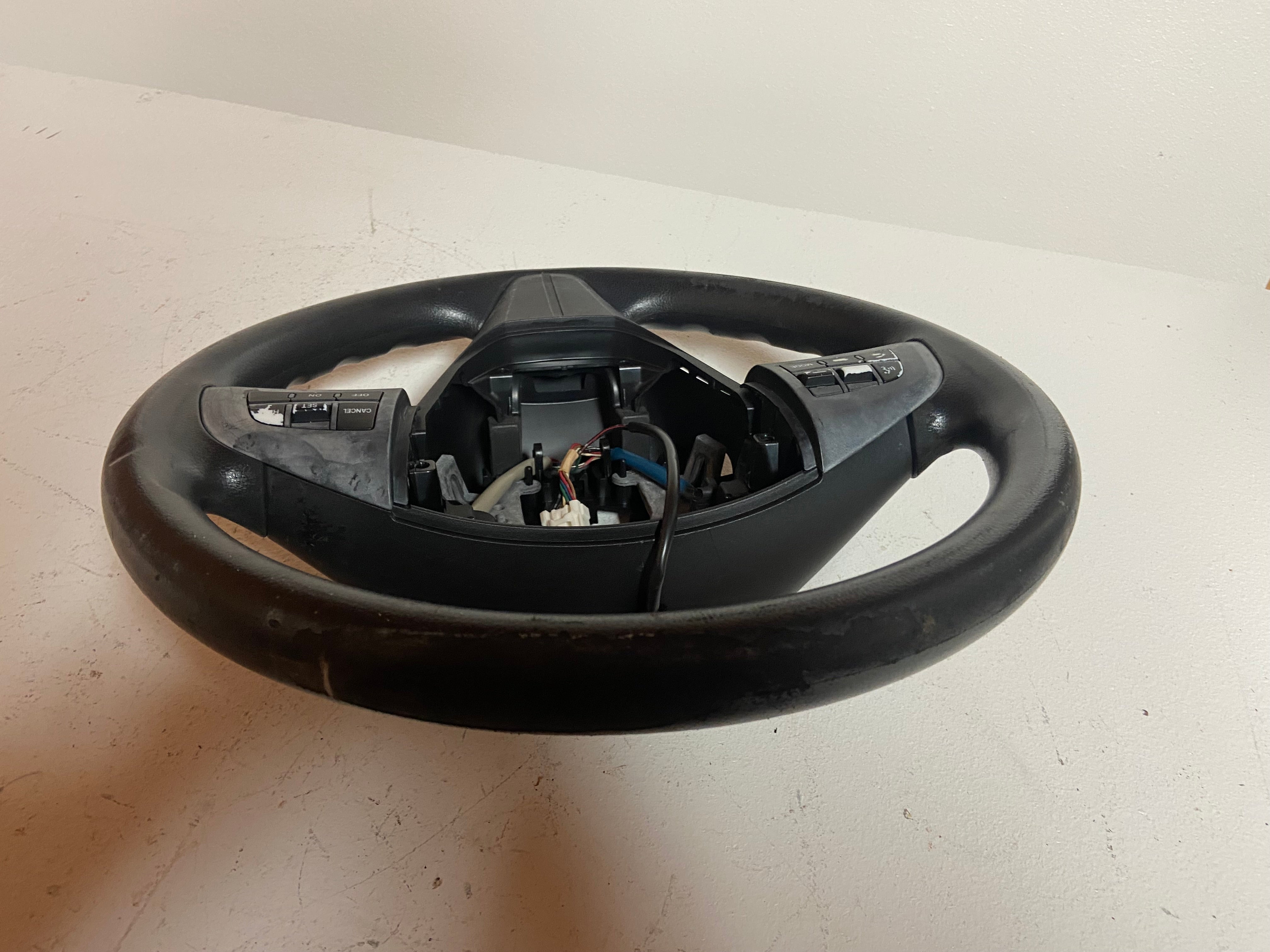 Black OEM steering wheel for 2010 Mazda 3 touring, rear view with switch modules visible