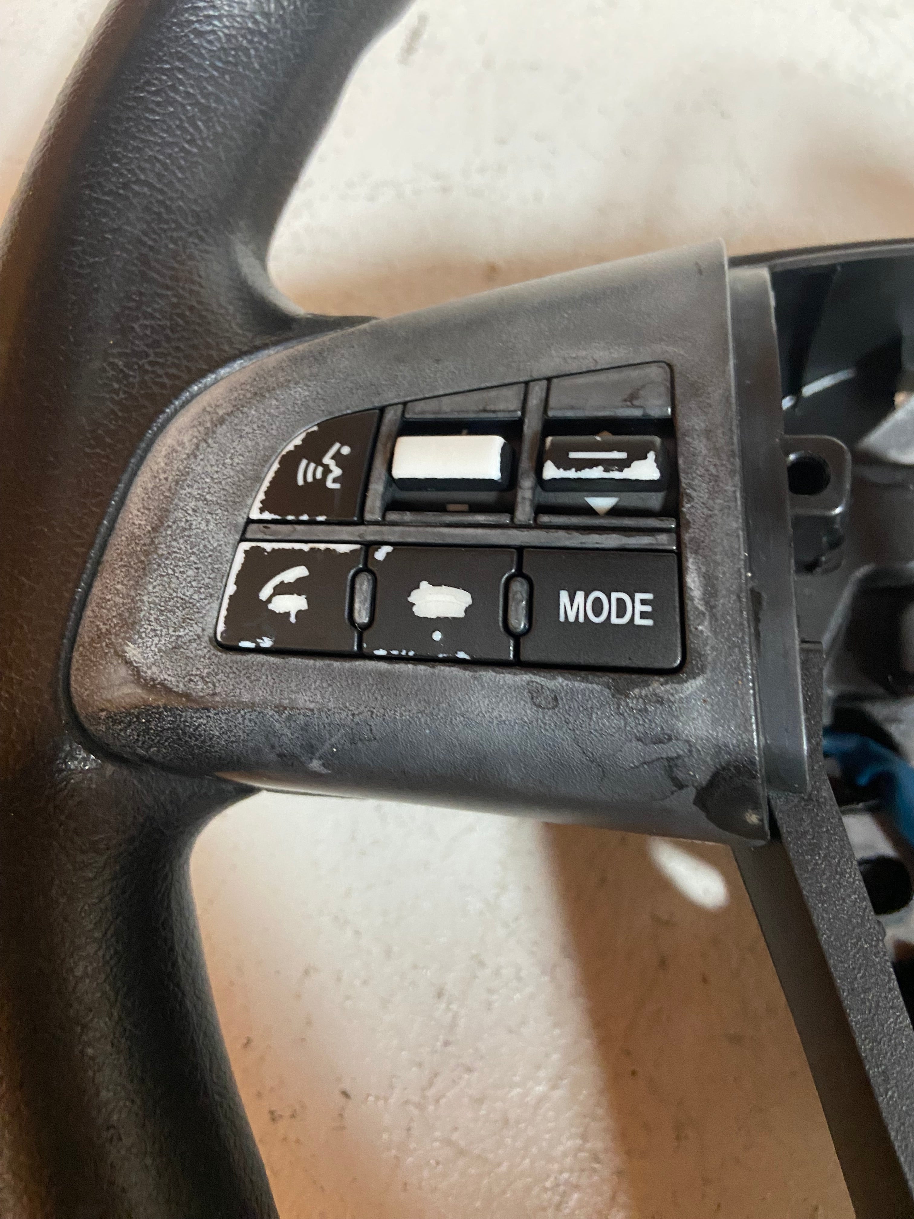Black steering wheel control buttons with icons and MODE, plus arrow-like switches