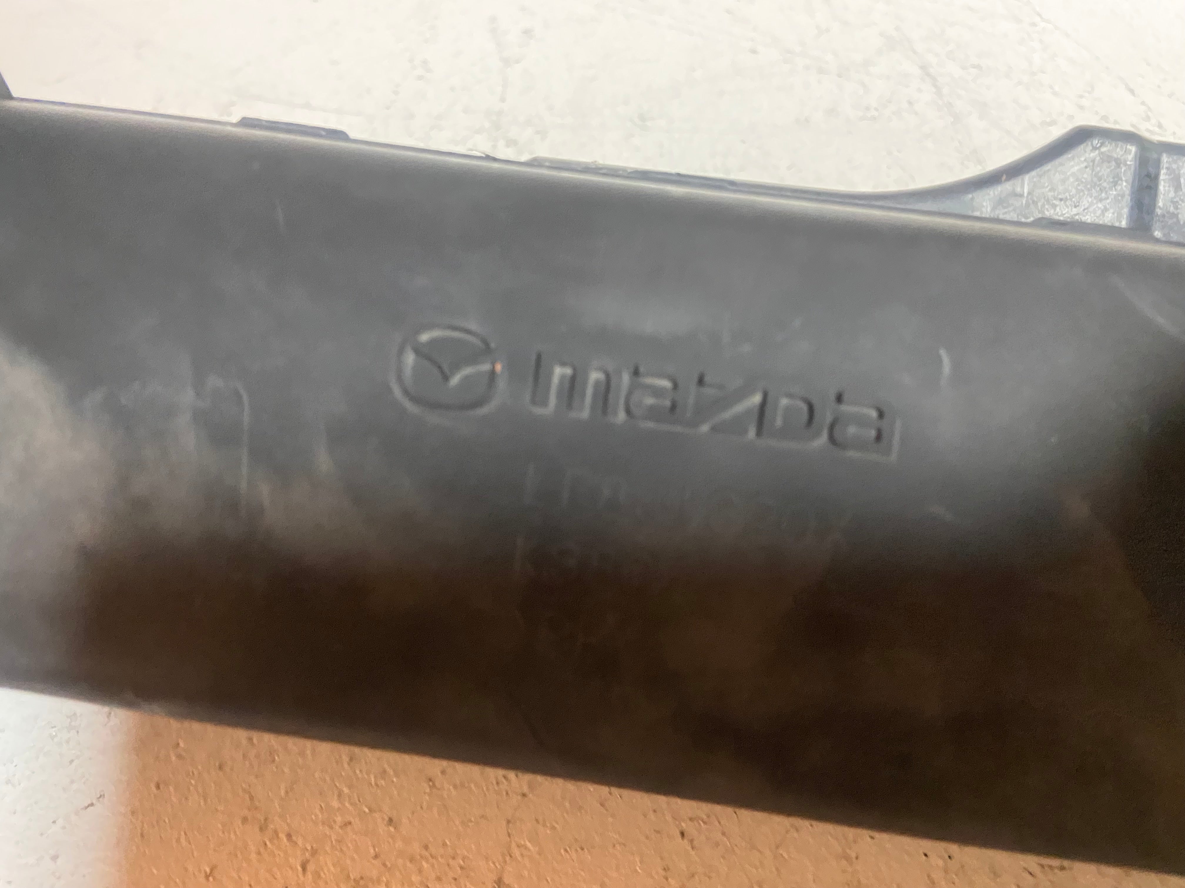 Black plastic air intake duct with Mazda lettering and logo