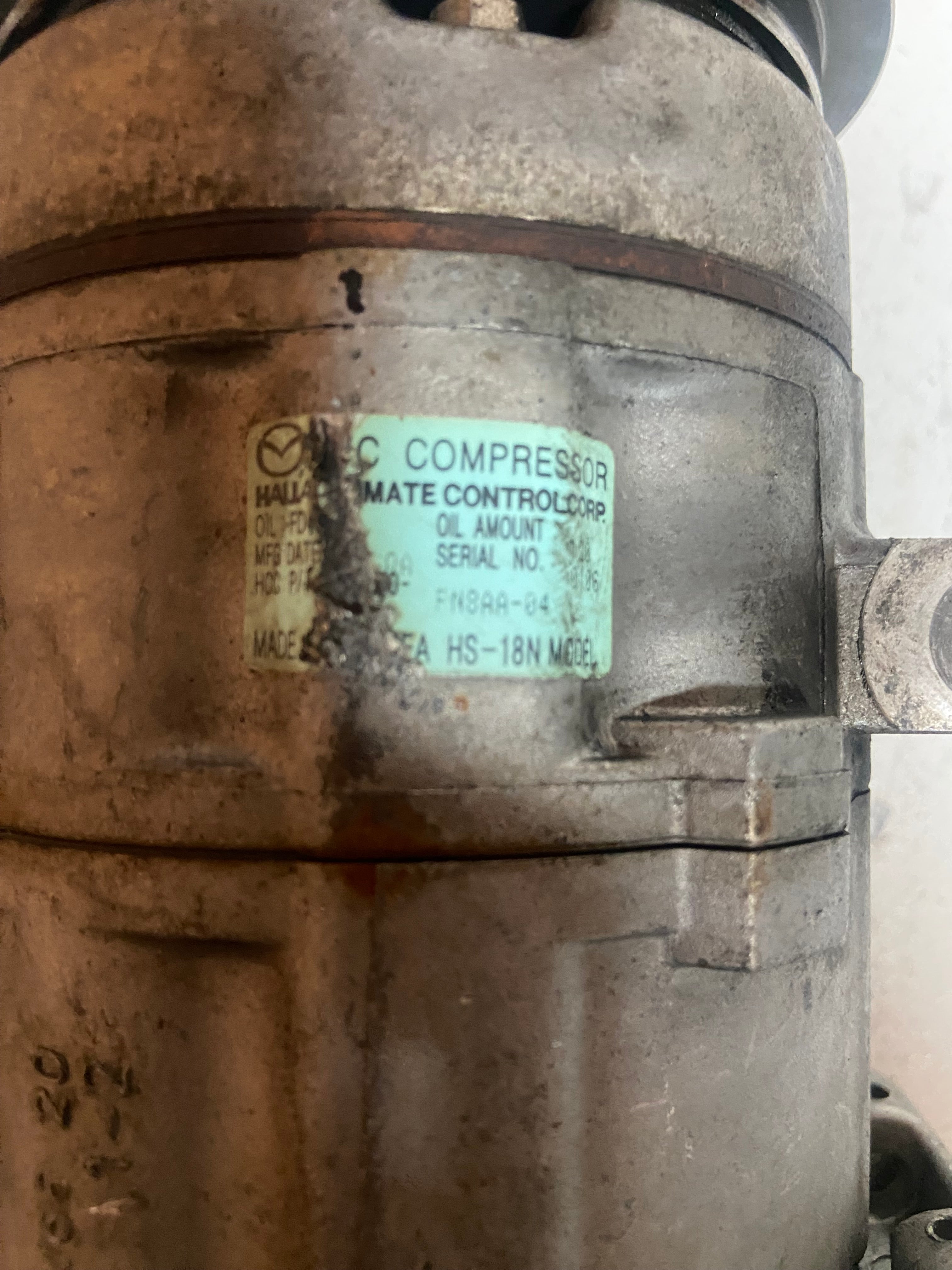 A/C compressor housing with technical label and oil amount text