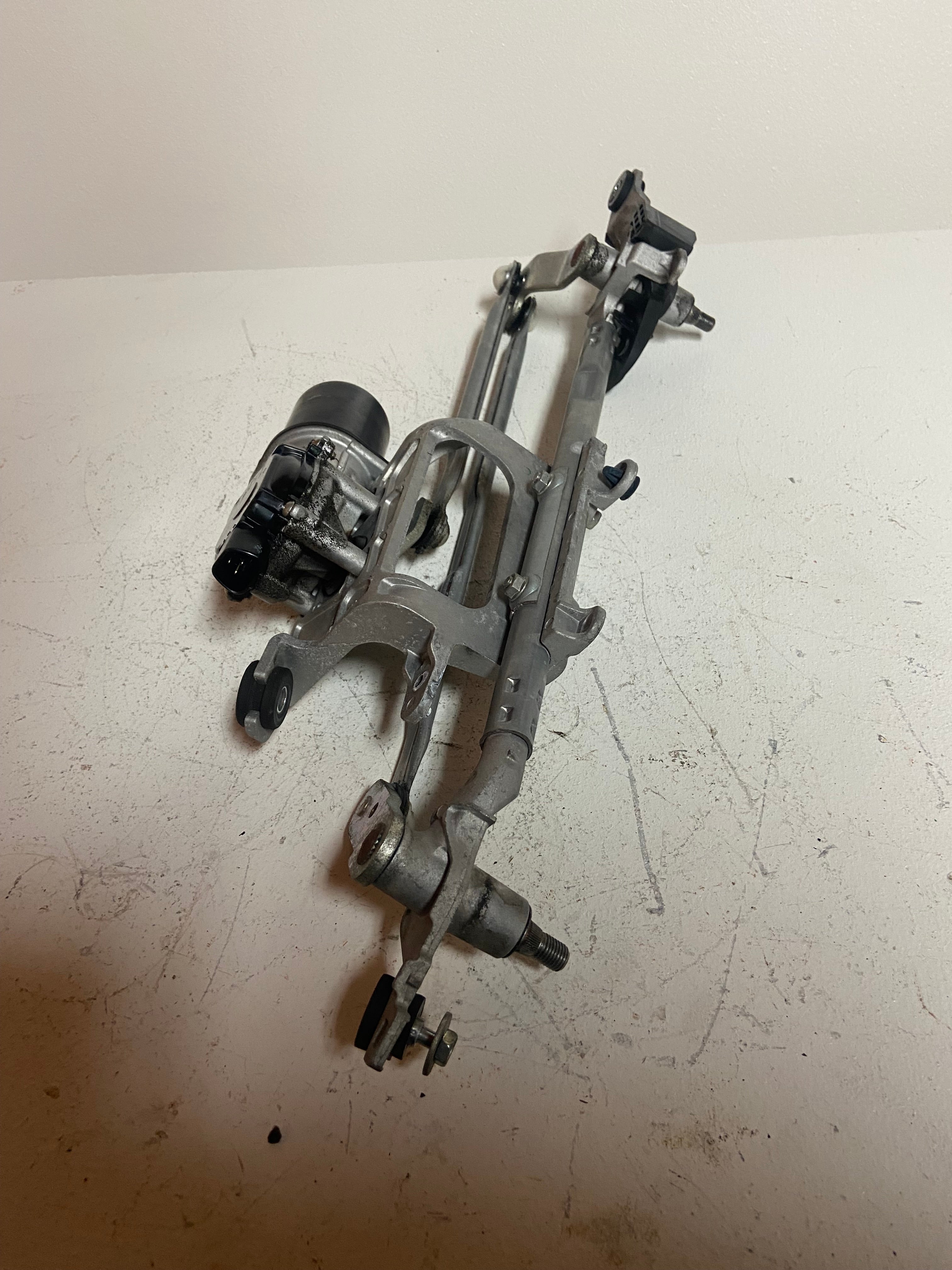 Windshield wiper motor linkage assembly with black motor cover and mounting studs