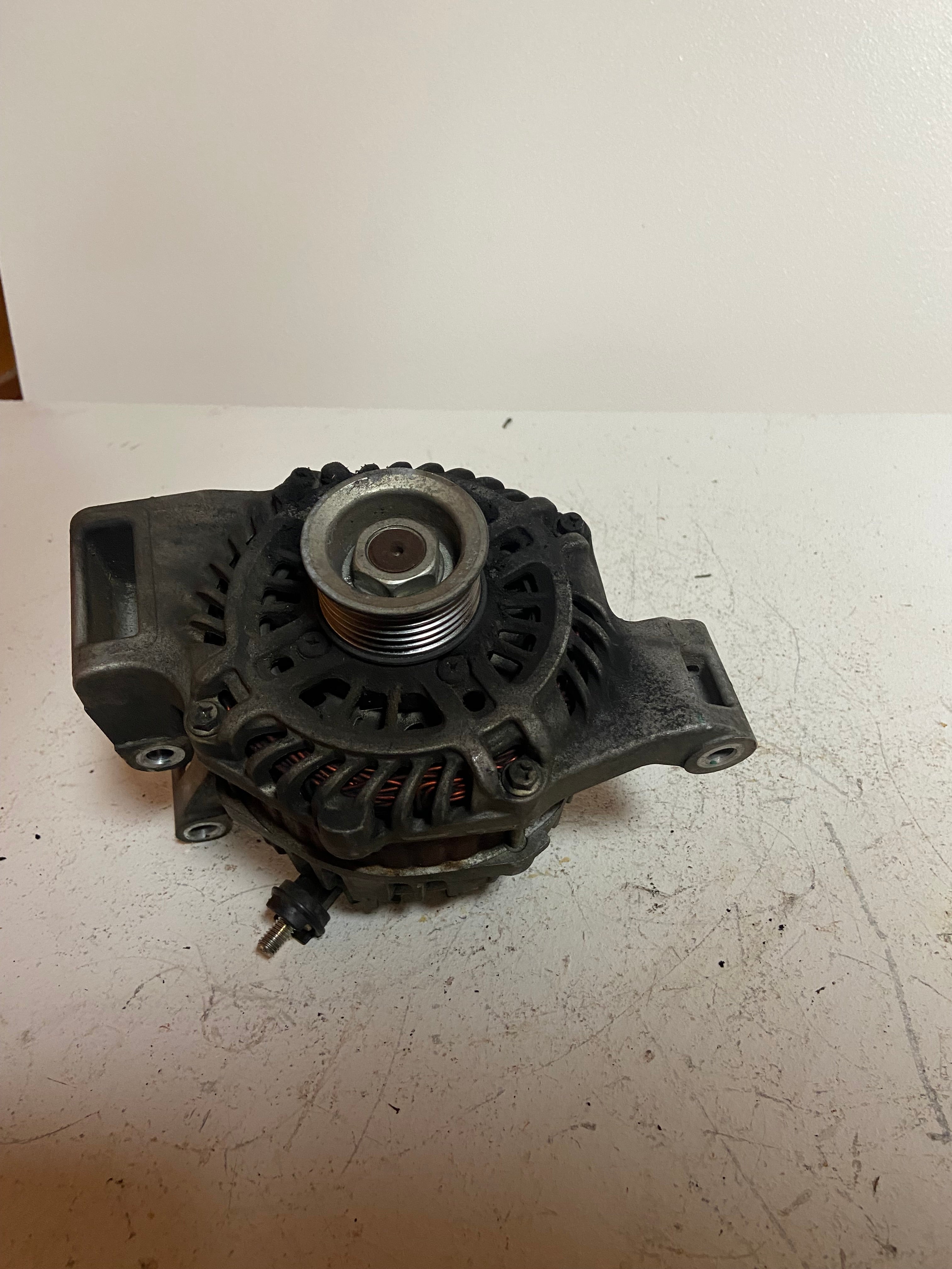 Alternator front view with central pulley nut and fan vents, gray housing