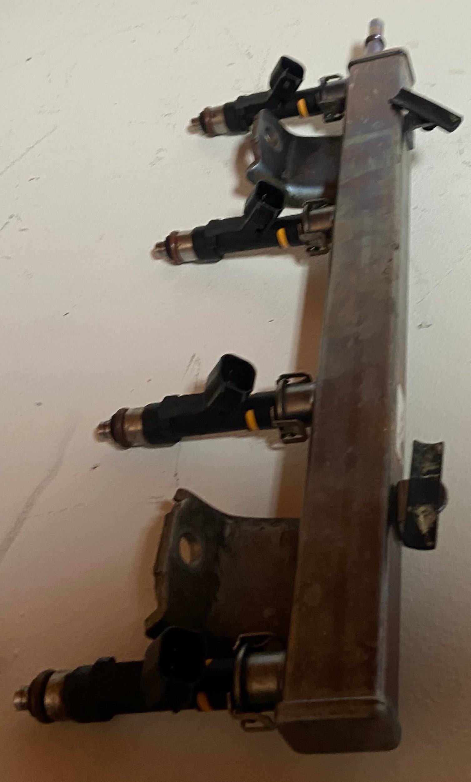 Engine fuel rail with visible black injector connectors and metal manifold block
