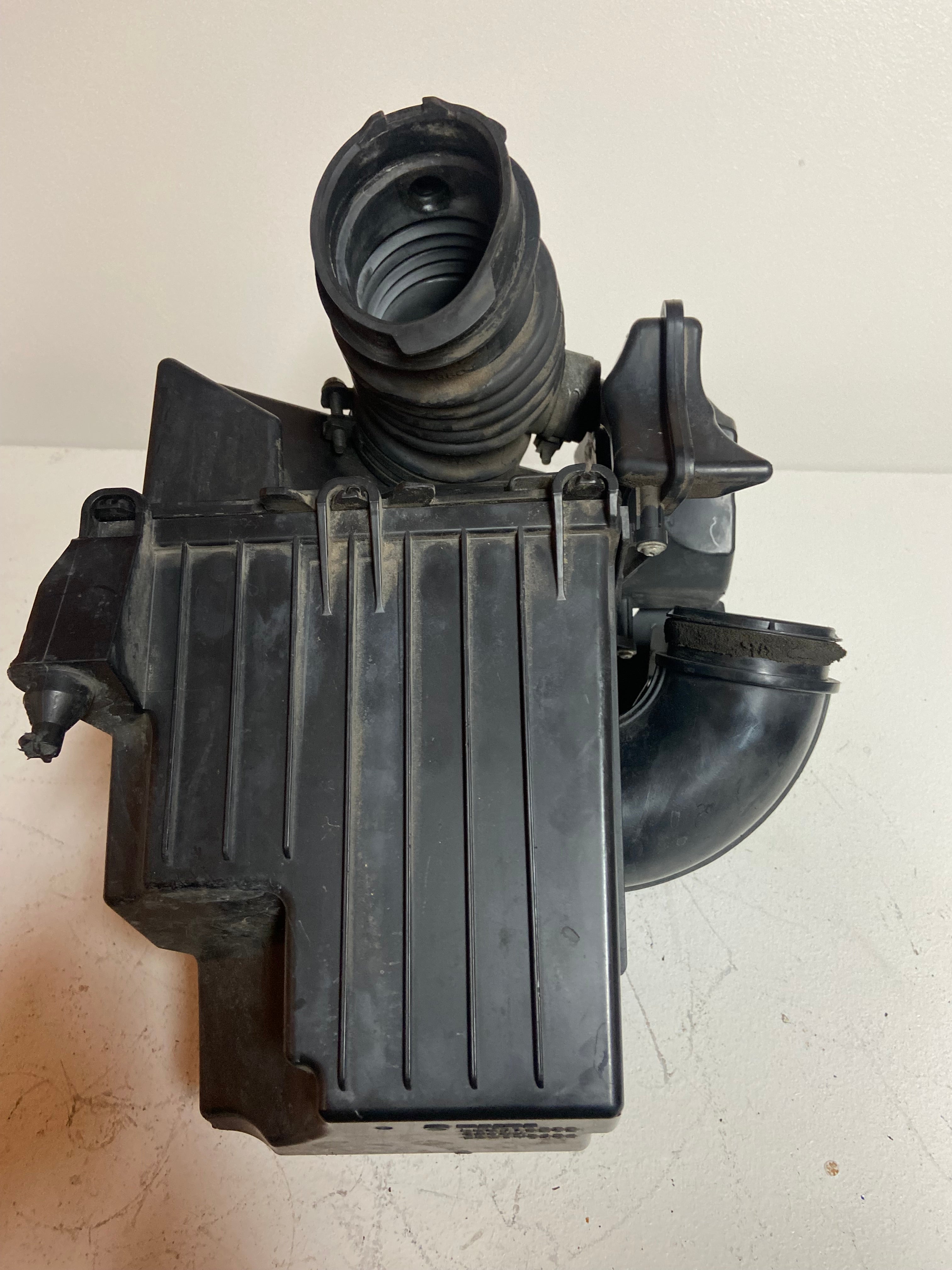 Air intake filter box housing with ribbed sides and intake duct elbow
