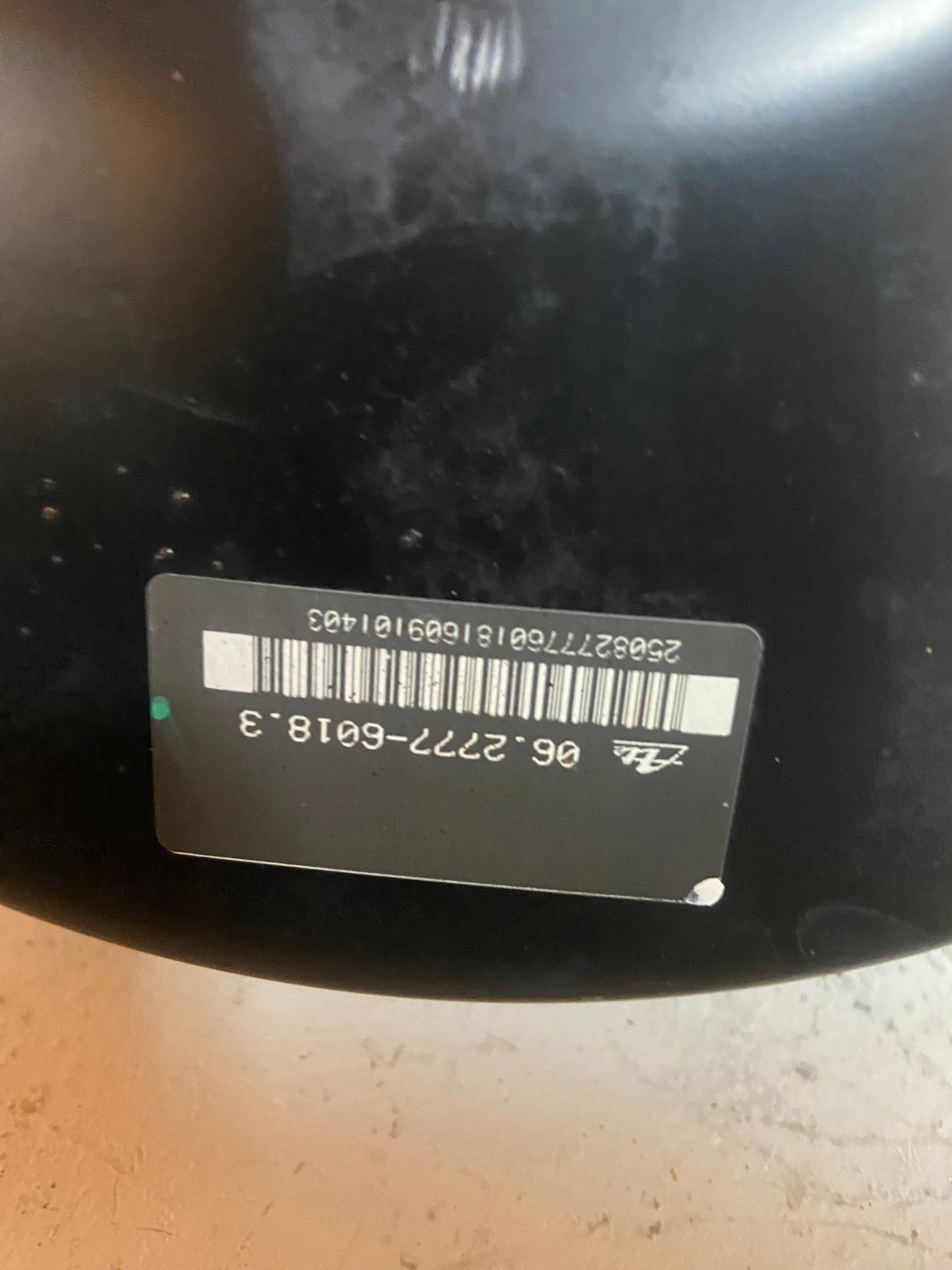 Black brake booster housing with barcode label and mounting stud holes