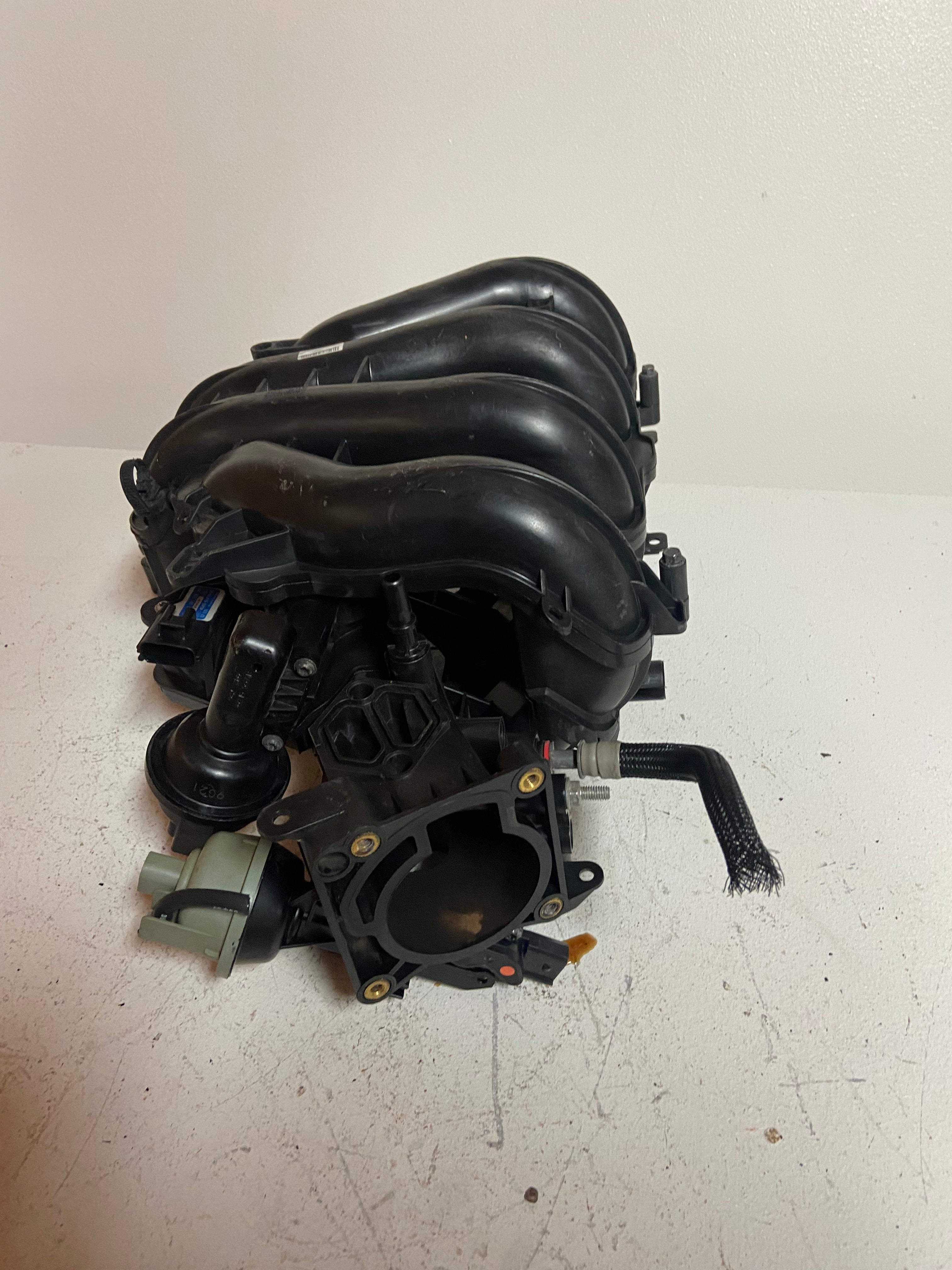 Engine air intake manifold assembly with black intake tubes and mounting points