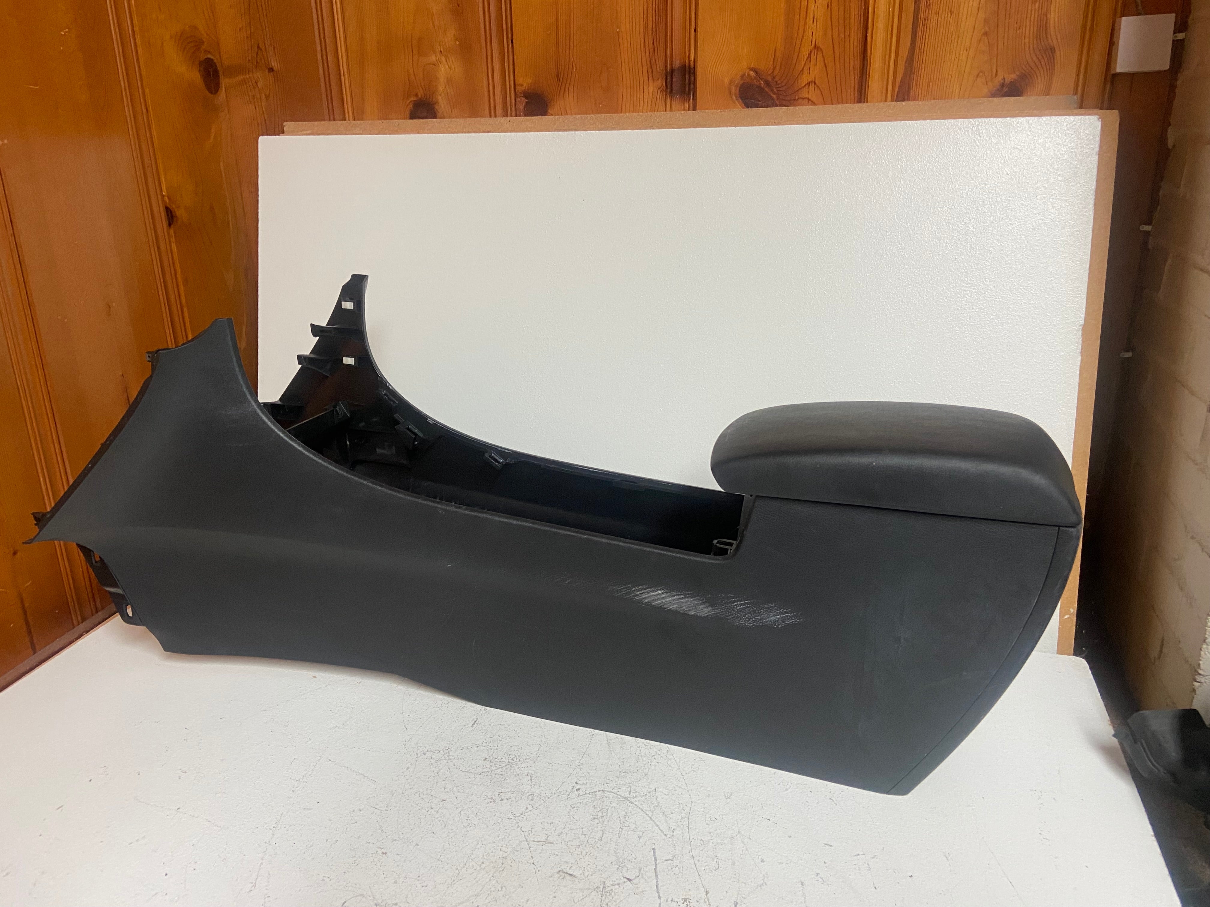 Black center console with curved armrest and side trim