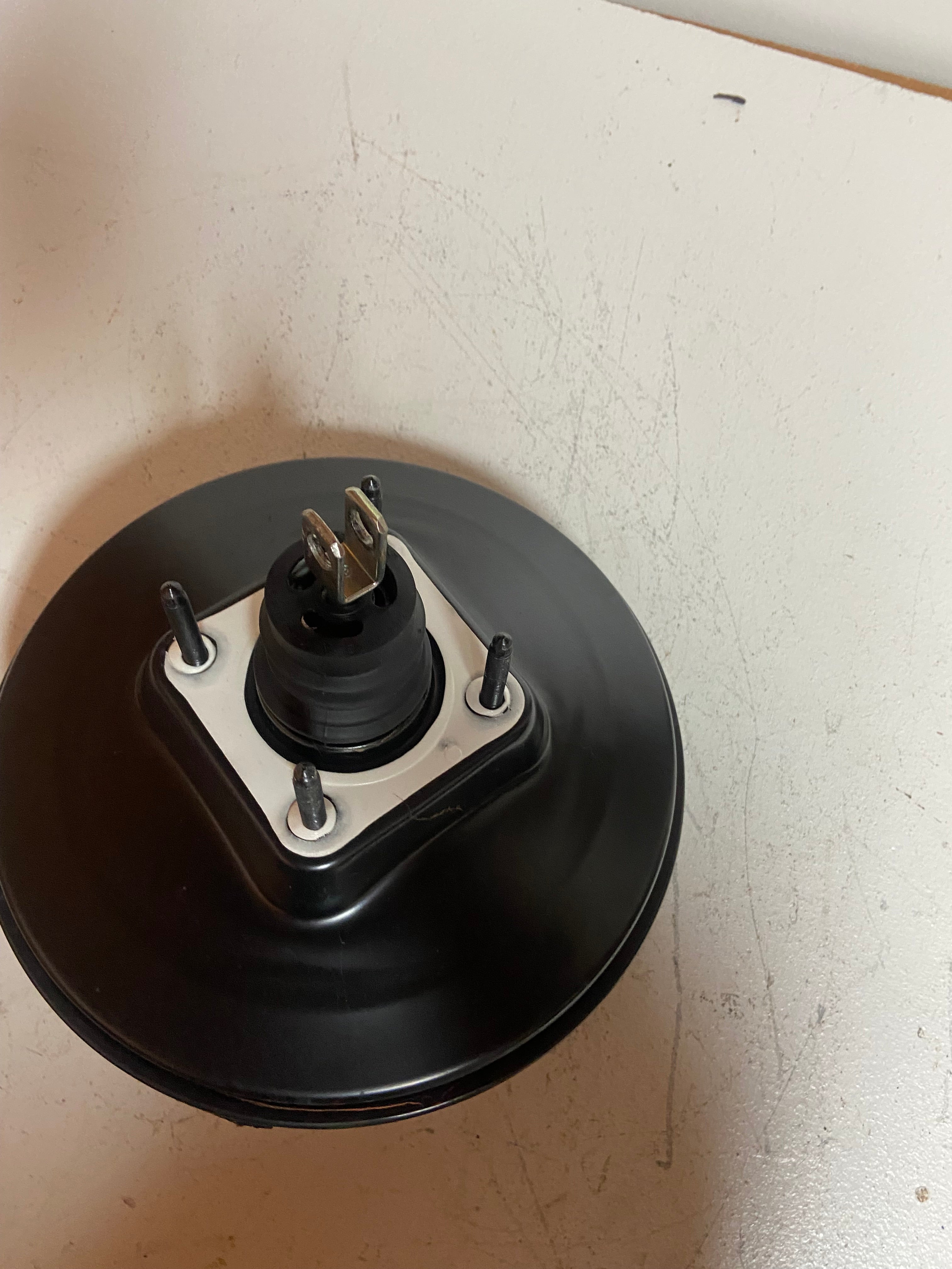Black brake booster with rubber diaphragm, metal base plate, and three studs