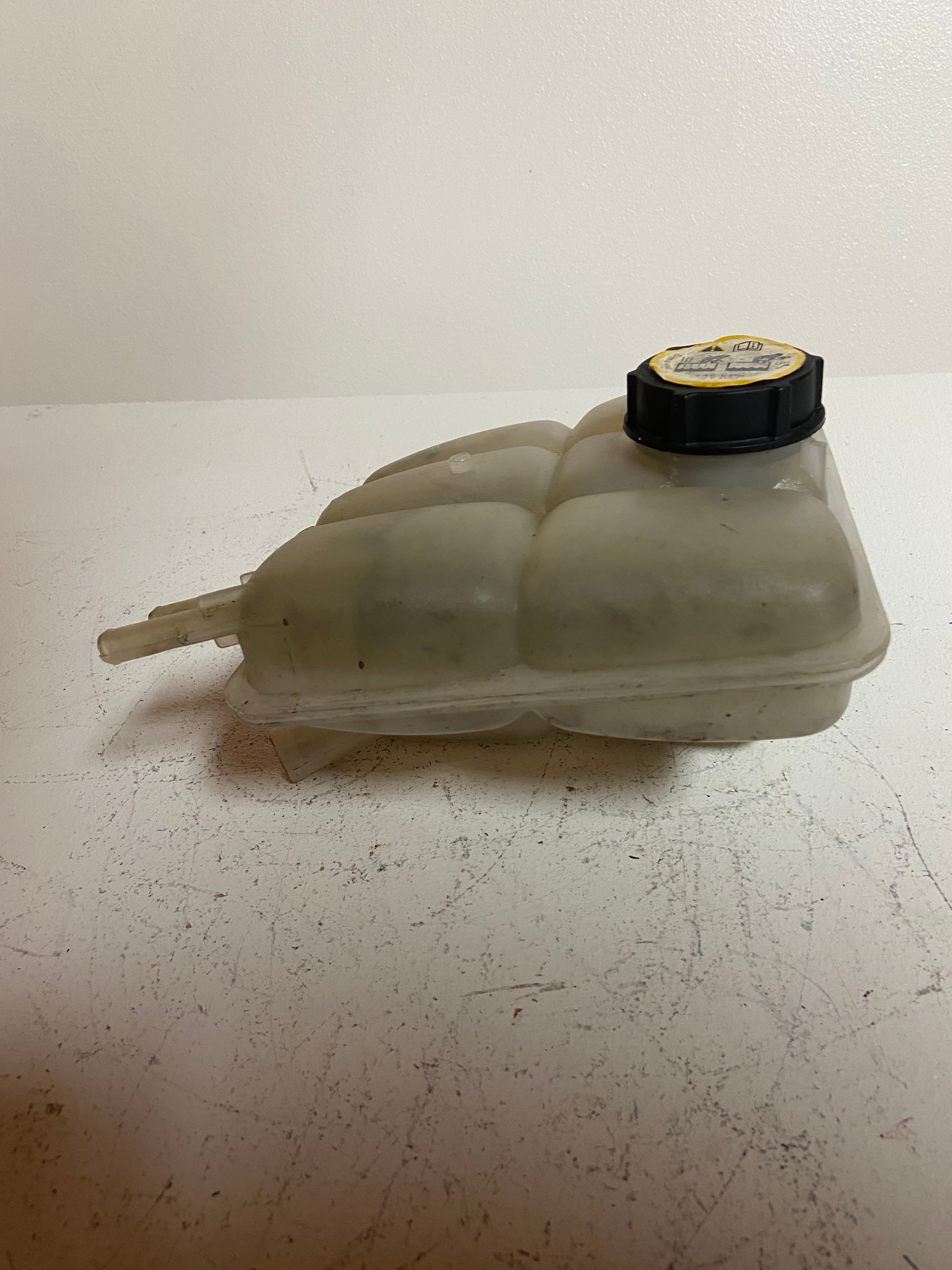 Engine coolant reservoir tank with black cap and light gray plastic side outlet