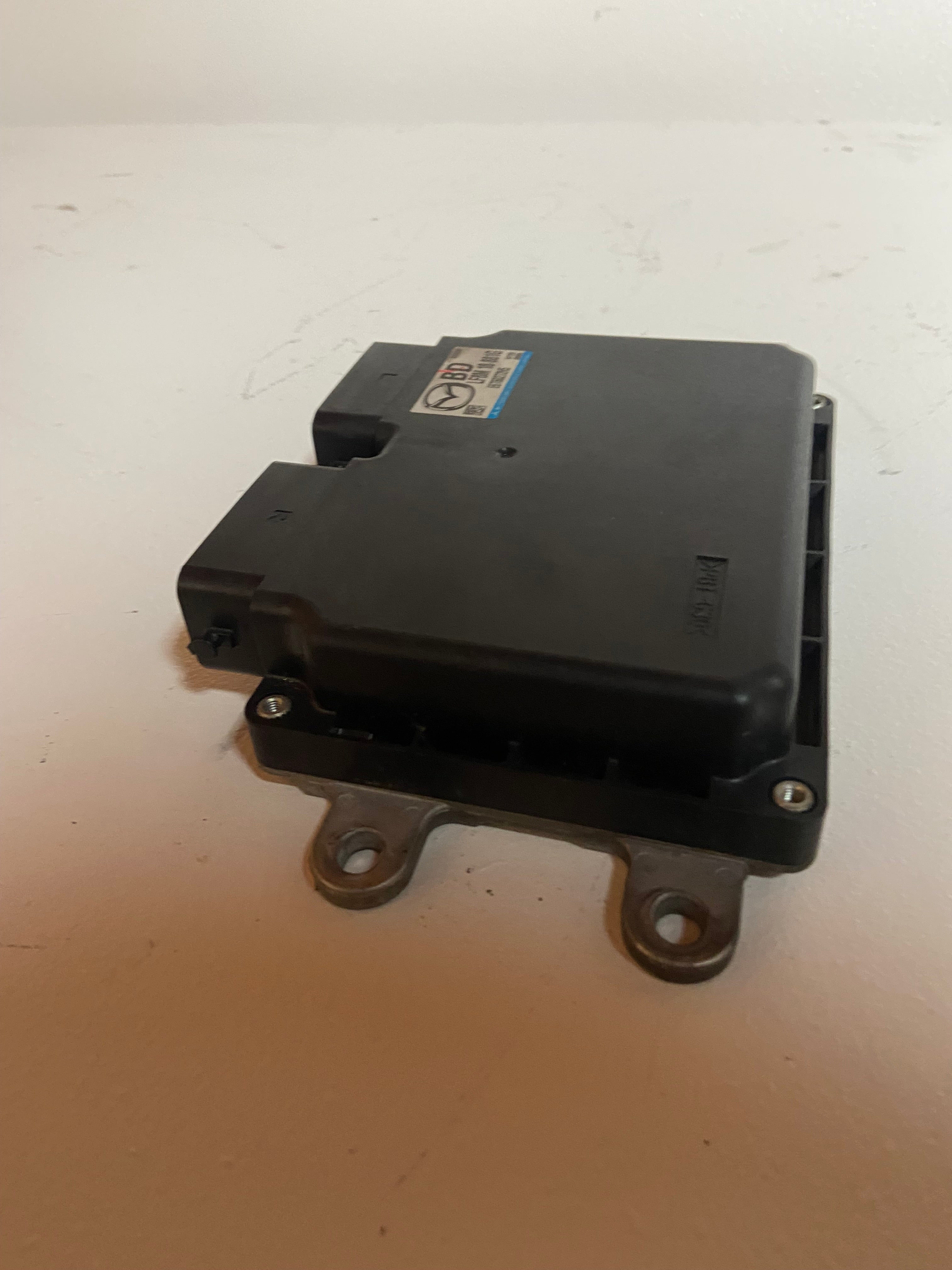 Black engine control module with top label and three metal mounting loops