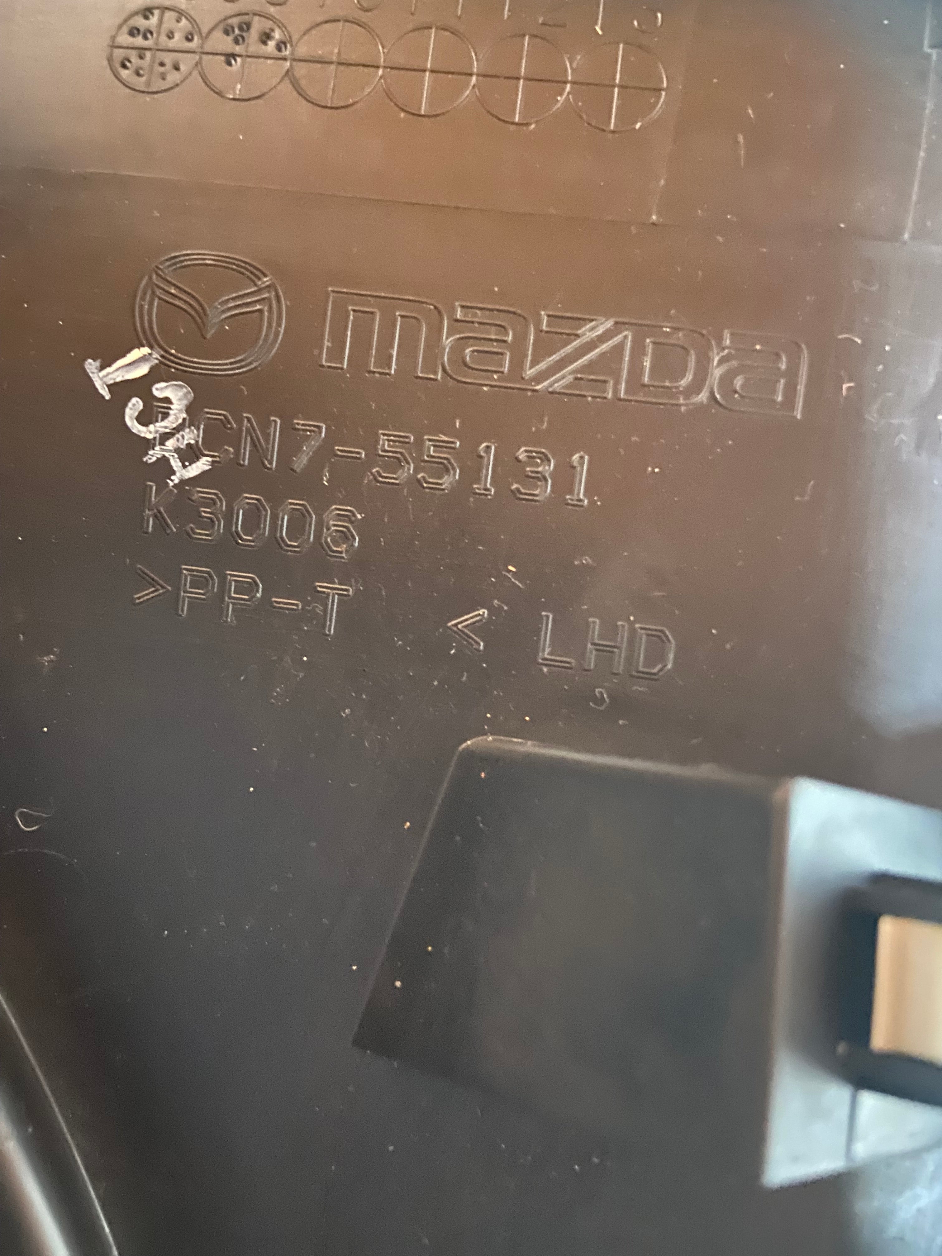 Mazda instrument cluster trim bezel with stamped part markings, dark finish