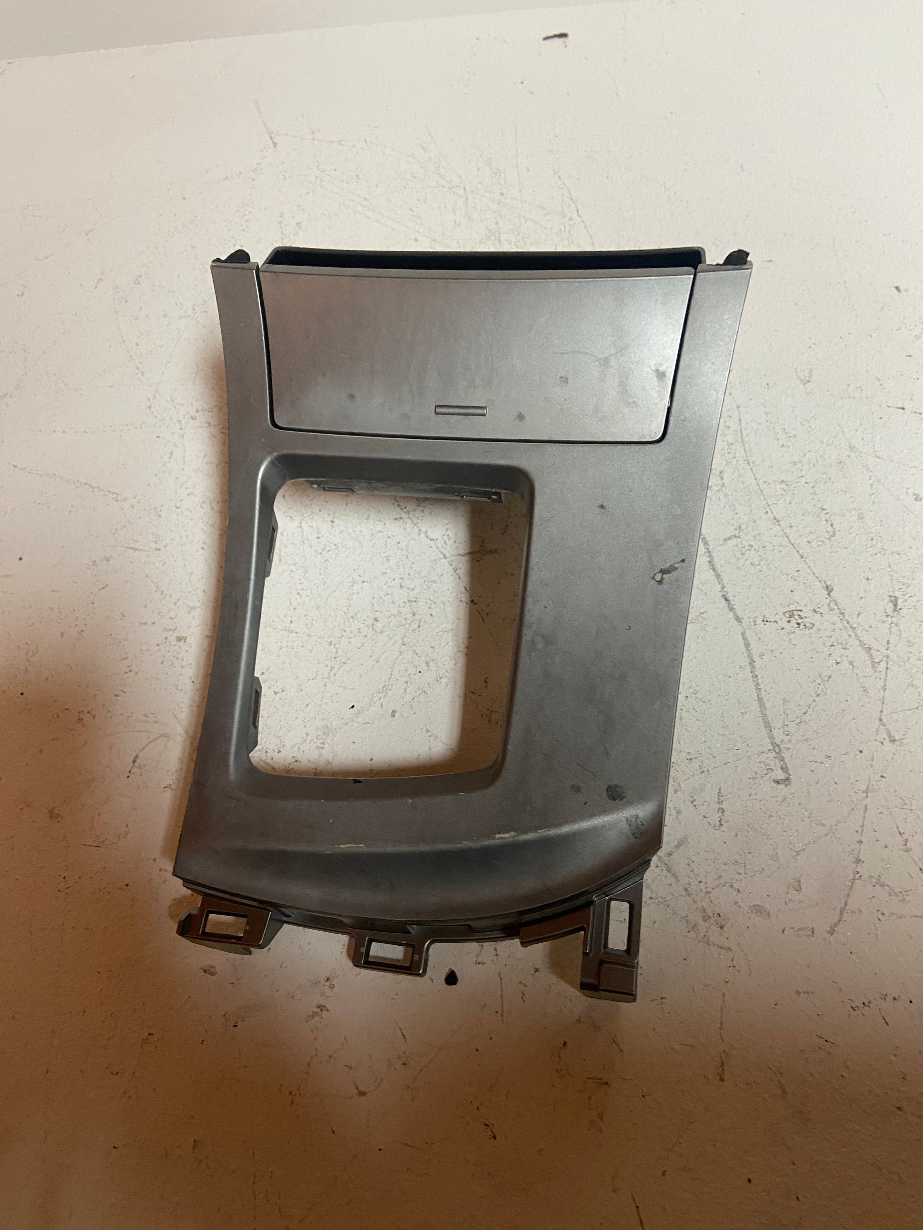 Silver center console trim bezel with large square opening and thin lower slot