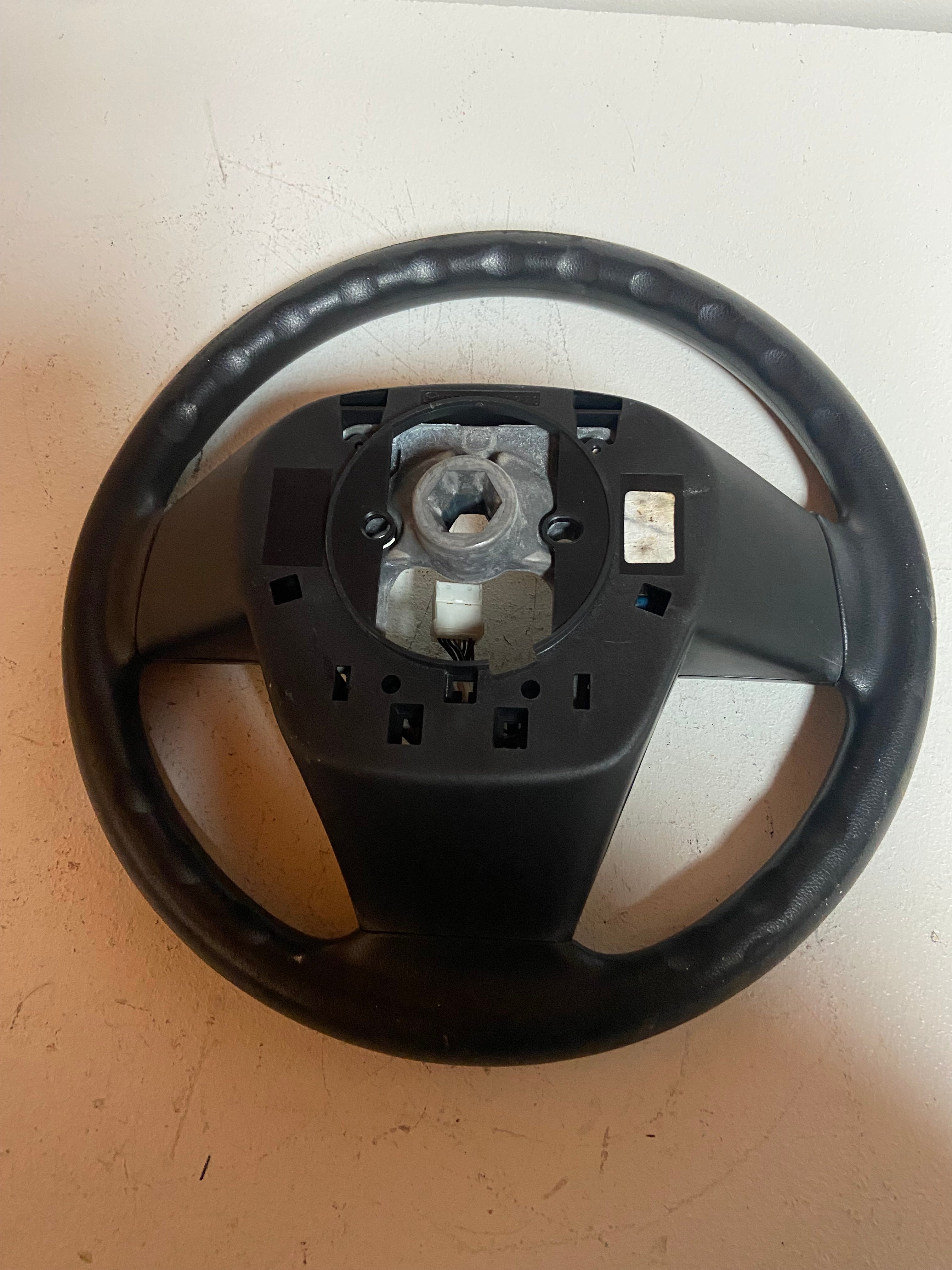 Black OEM steering wheel for 2010 Mazda 3 touring, hub area close-up with mounting plate