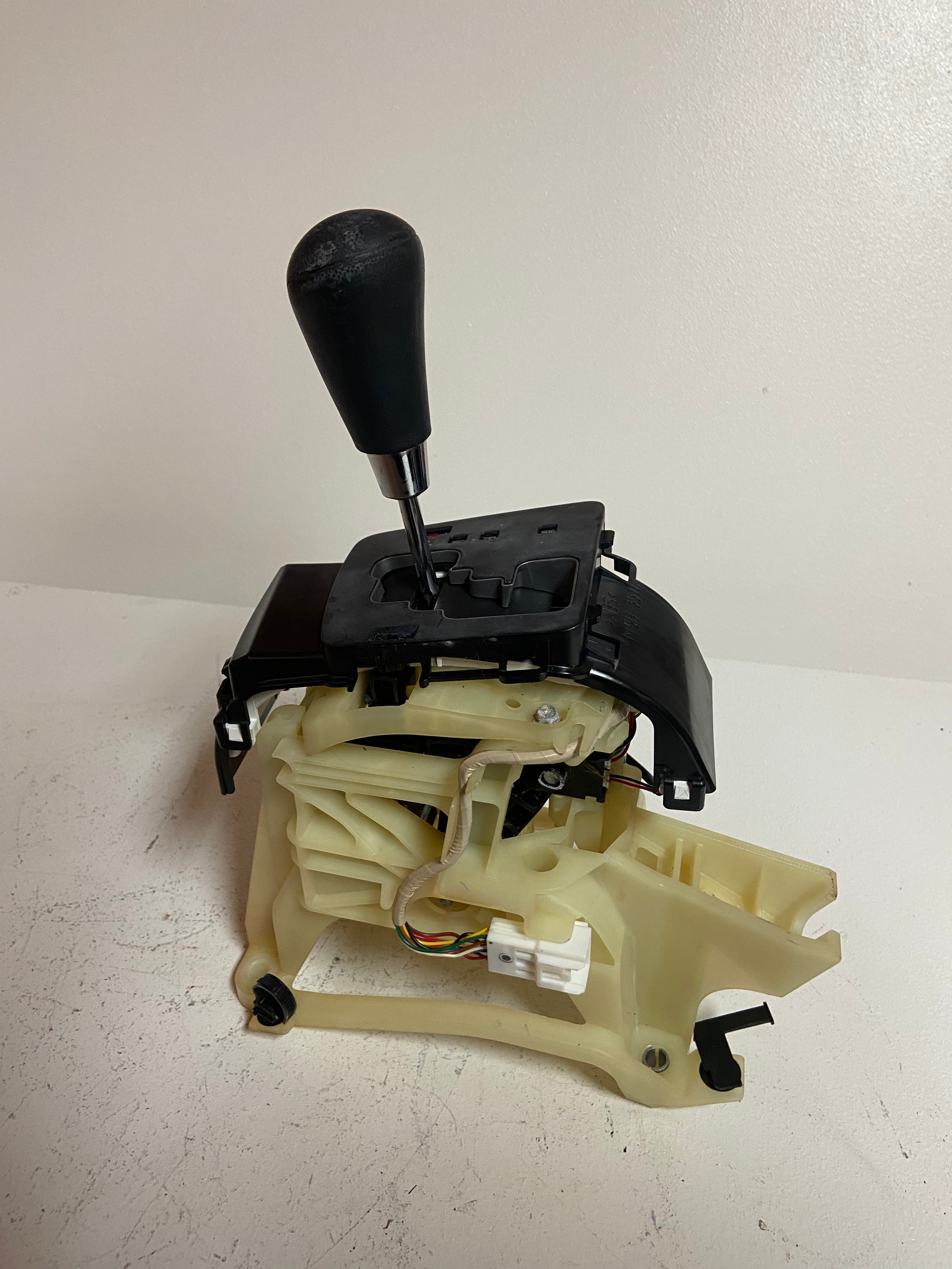 Automatic transmission shifter base with black shift lever and beige internal parts
